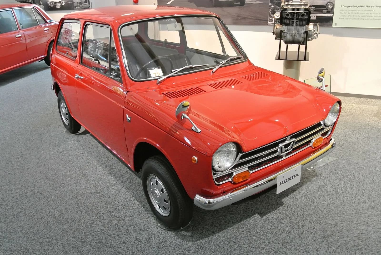 ホンダN360を斜め前から。赤い小さな軽自動車。展示施設の展示車