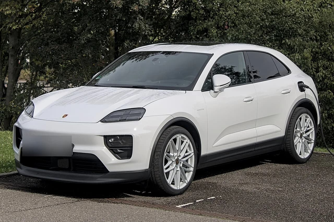 充電ケーブルをつないだポルシェ・マカン（EV世代）を斜め前から。白いSUV