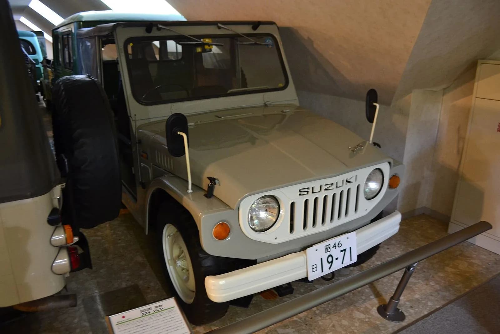 初代スズキ・ジムニー（1971年製）を斜め前から。ベージュの小さな角ばった四輪駆動車。博物館の展示車