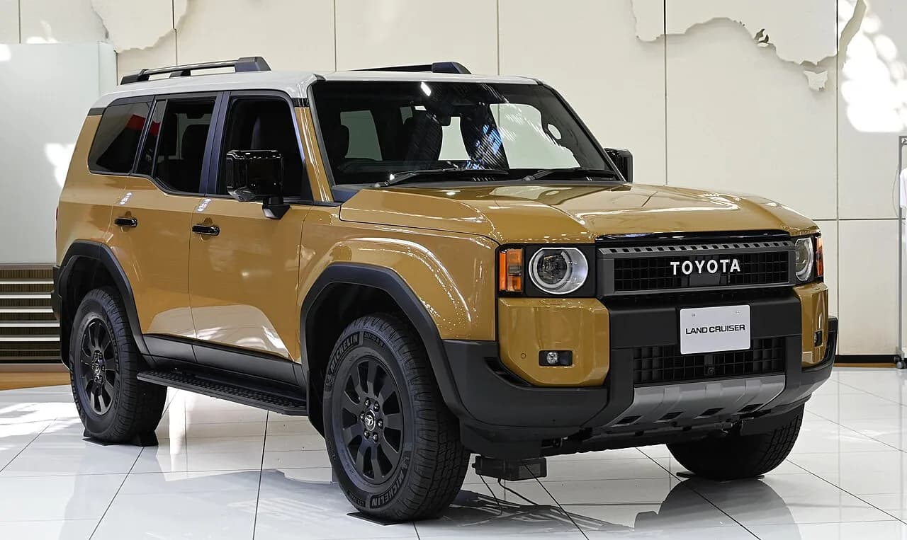 展示されたトヨタ・ランドクルーザー250を斜め前から。丸型ヘッドライトのベージュの大型SUV
