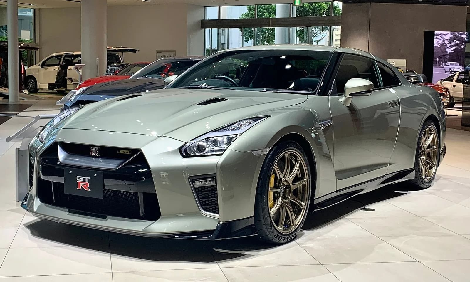 日産GT-R（R35型・2021年）を斜め前から。淡い緑がかったグレーのクーペ。展示車