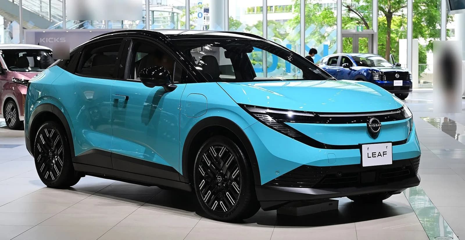 3代目日産リーフ（2026年）を斜め前から。水色の車体に黒い屋根。ショールームの展示車