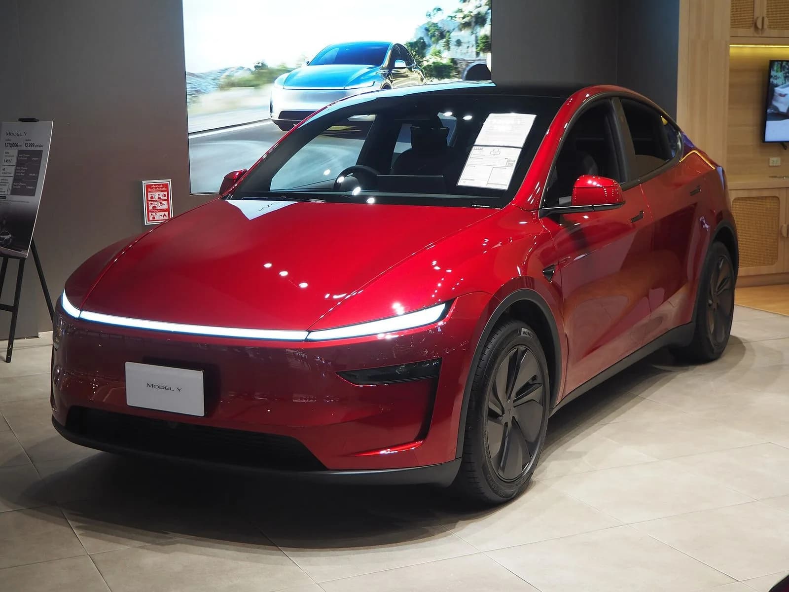 テスラ モデルY（2025年改良型）を斜め前から。赤い車体。店舗の展示車