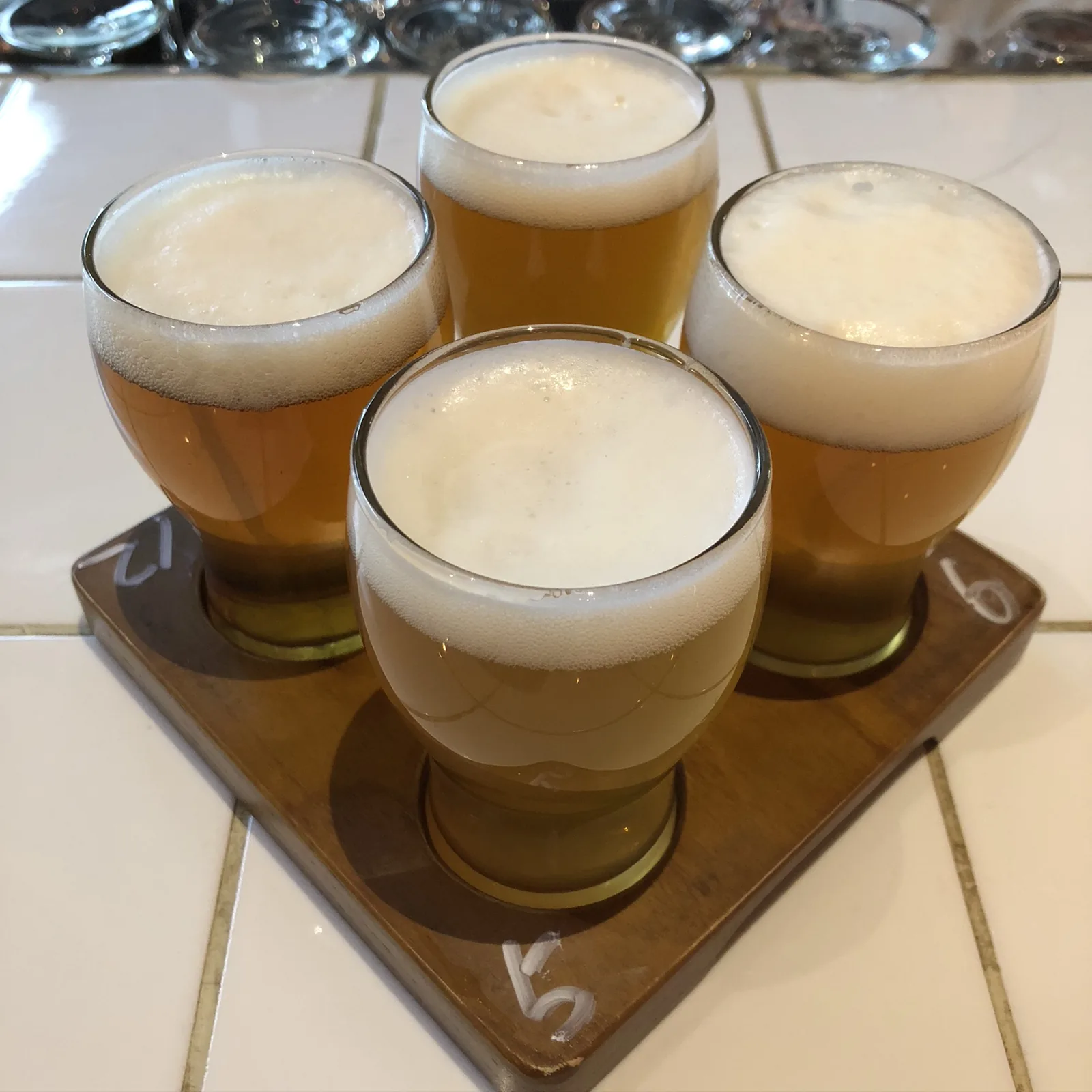 木の台に載った4つの小さなグラス。それぞれ色の違うビールが注がれている