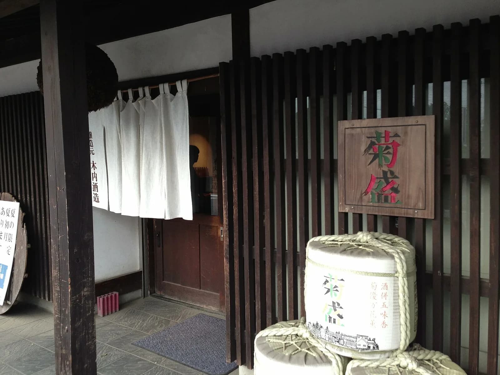 木内酒造の入口。木の看板に菊盛の文字、酒樽と暖簾が見える