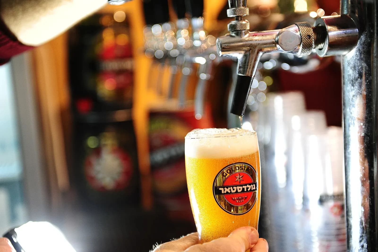 タップからグラスへビールが注がれる瞬間。グラスの中で泡が立ち上がる