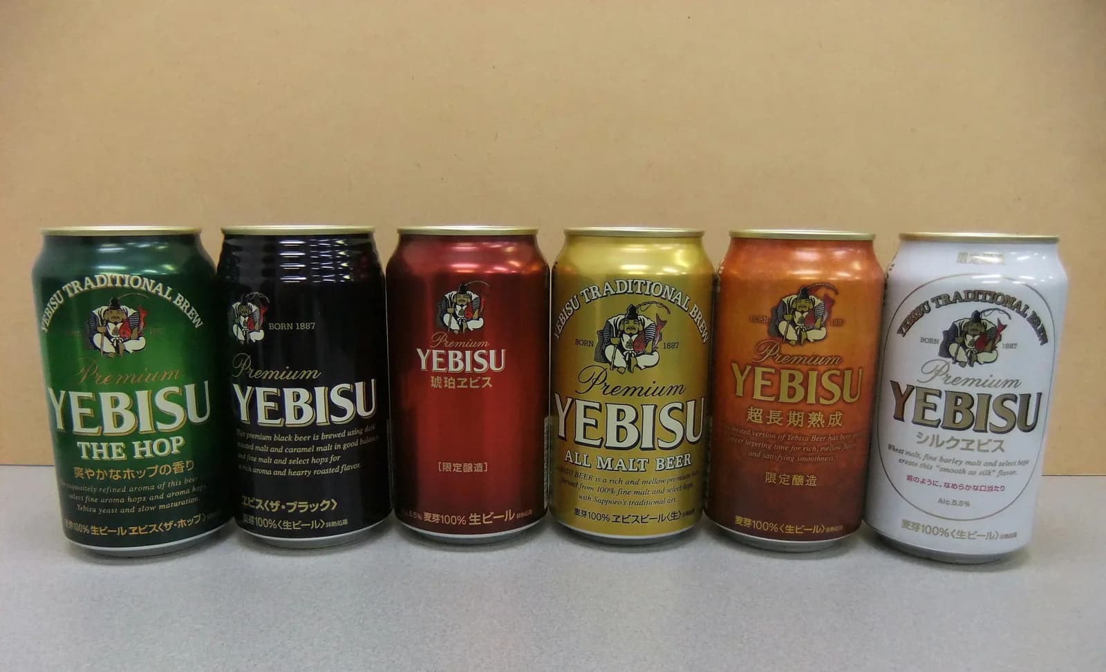 ヱビスの缶6種が横一列に並ぶ。緑、黒、赤、金、銅色、白の缶それぞれに恵比寿様の像