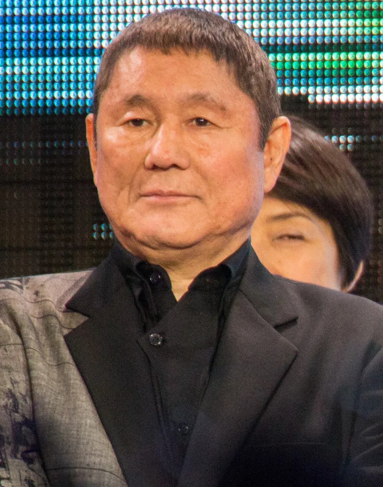 イベントの壇上でマイクを持つ年配の男性