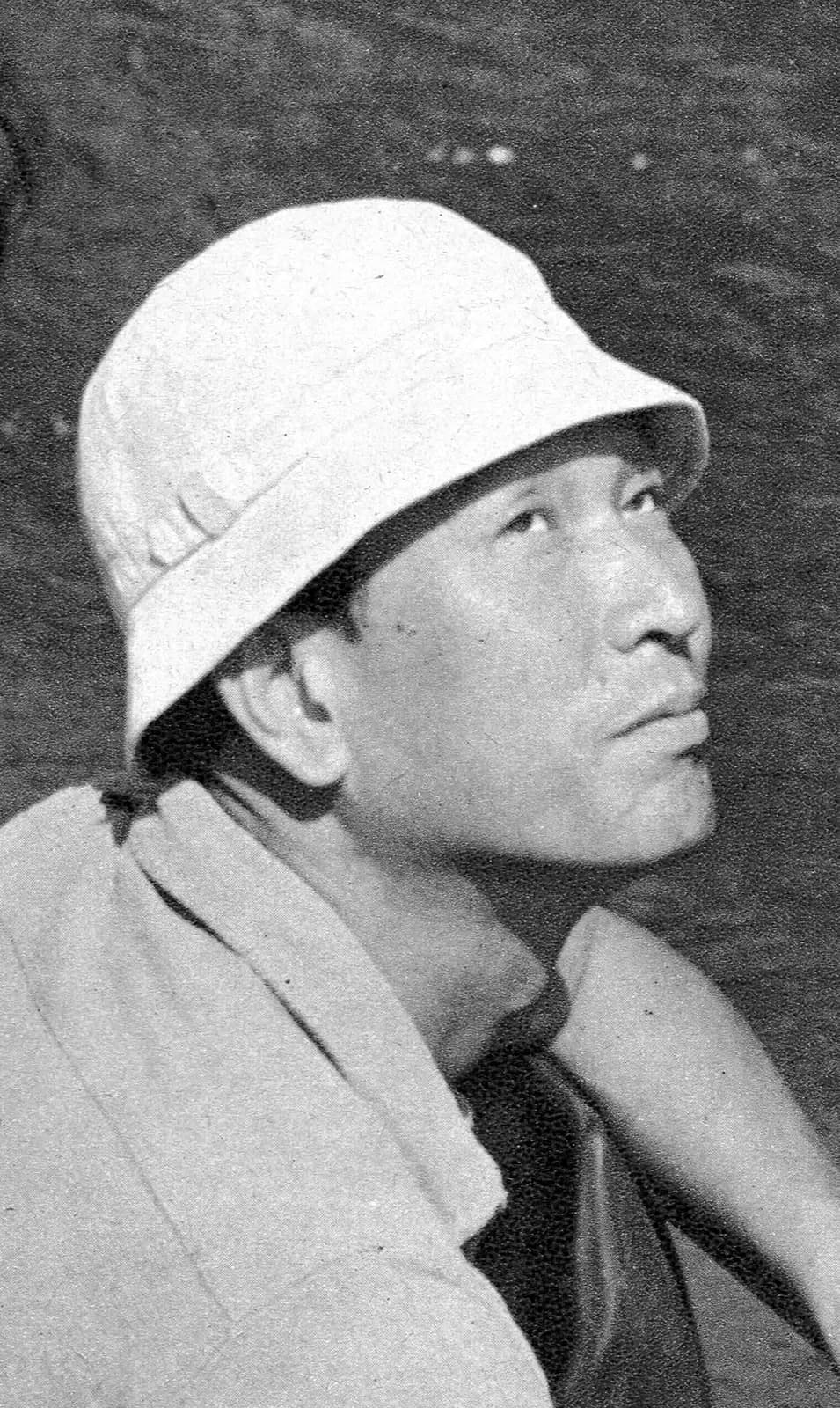 サングラスをかけ、腕を組んで現場に立つ監督の白黒写真