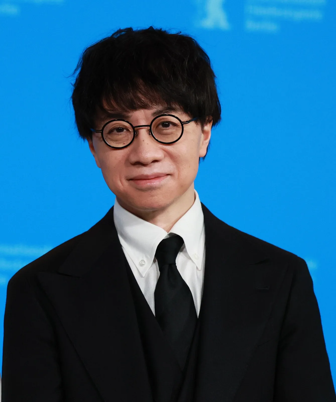 記者会見でマイクを前に話す眼鏡の男性