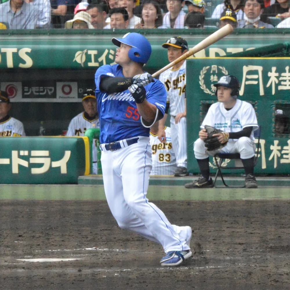 青いビジターユニフォームに背番号55の打者が、打球を見上げながらバットを振り抜いている