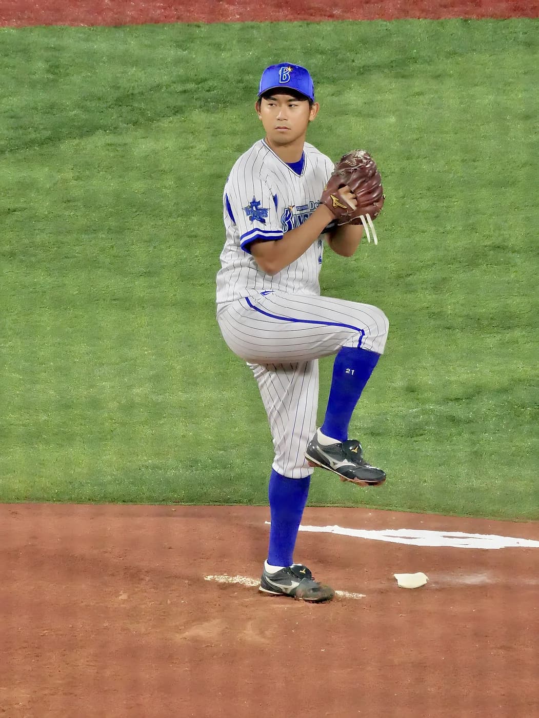 縦縞のユニフォームの左投手が、足を高く上げて投球動作に入っている