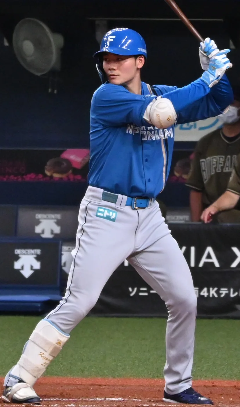 打席で構える打者。青いビジターユニフォームに「NIPPONHAM」の文字、白いヘルメットにFのマーク