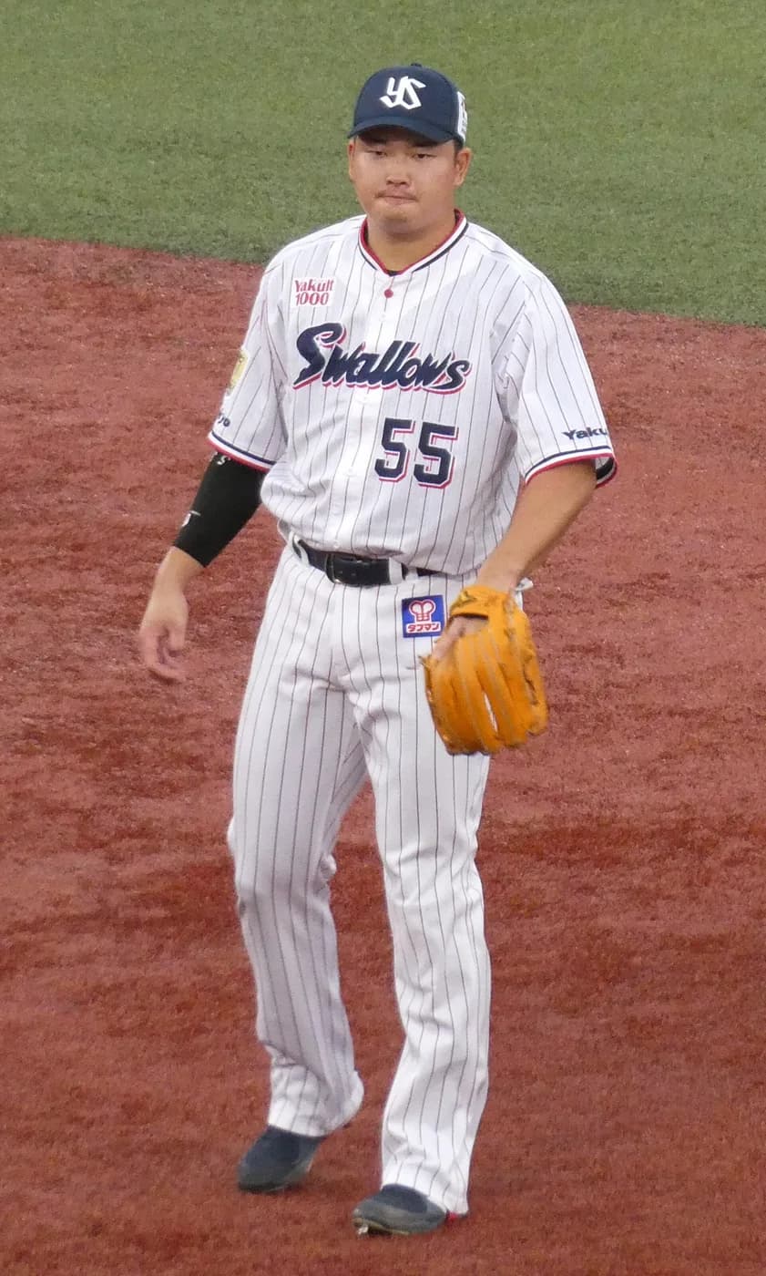白い縦縞のユニフォームに背番号55の大柄な内野手が、ミットを手にグラウンドに立っている