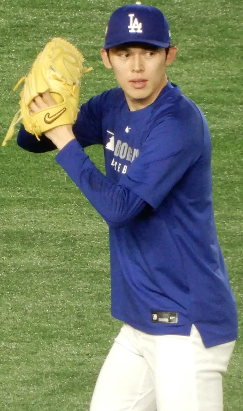 ドジャースの青い練習ウェアとLAキャップの若い投手が、黄色いグラブを構えて投球練習をしている