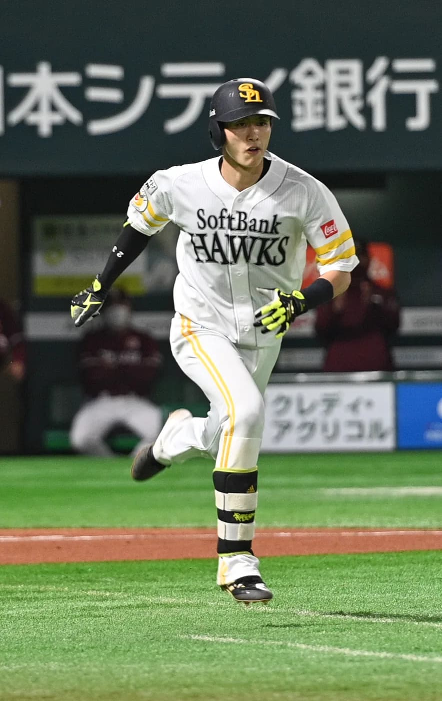 白いホームユニフォームの外野手が、バットを離して一塁へ走り出している