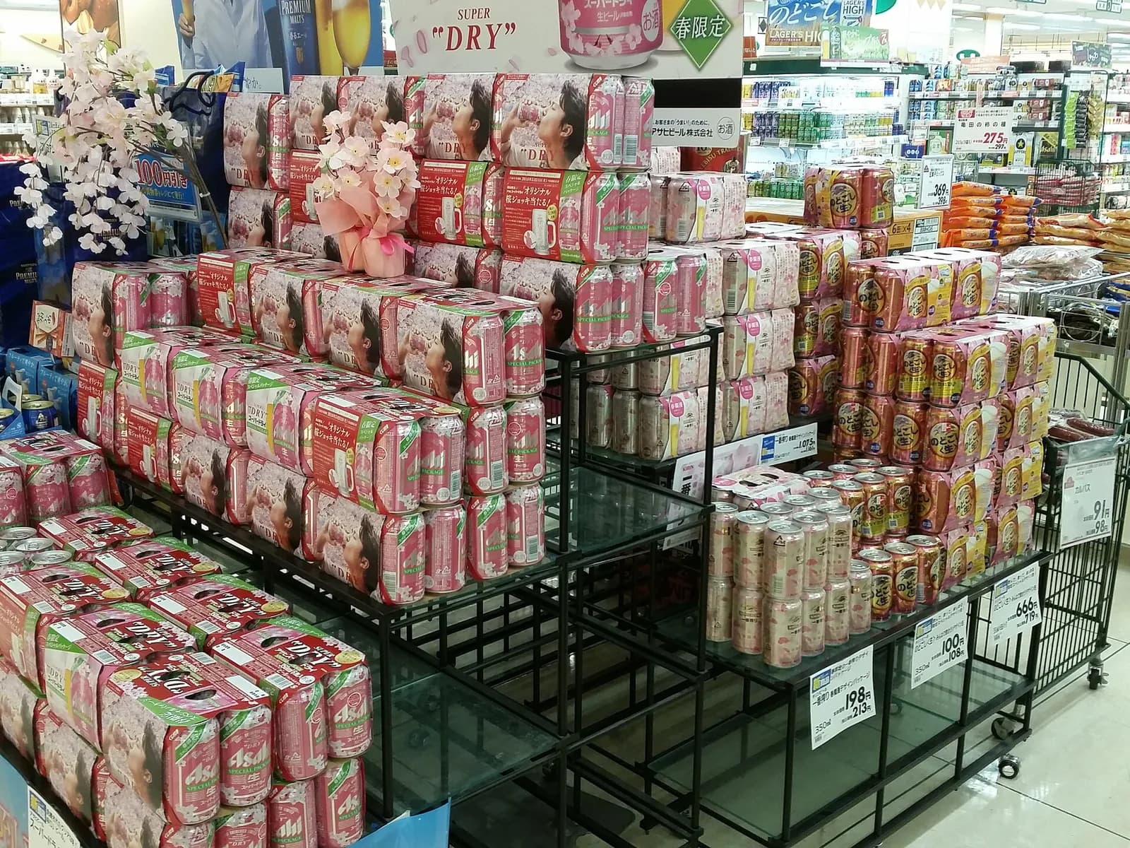 スーパーの特設売り場。桜デザインのスーパードライの箱が積まれ、春限定のPOPが立つ