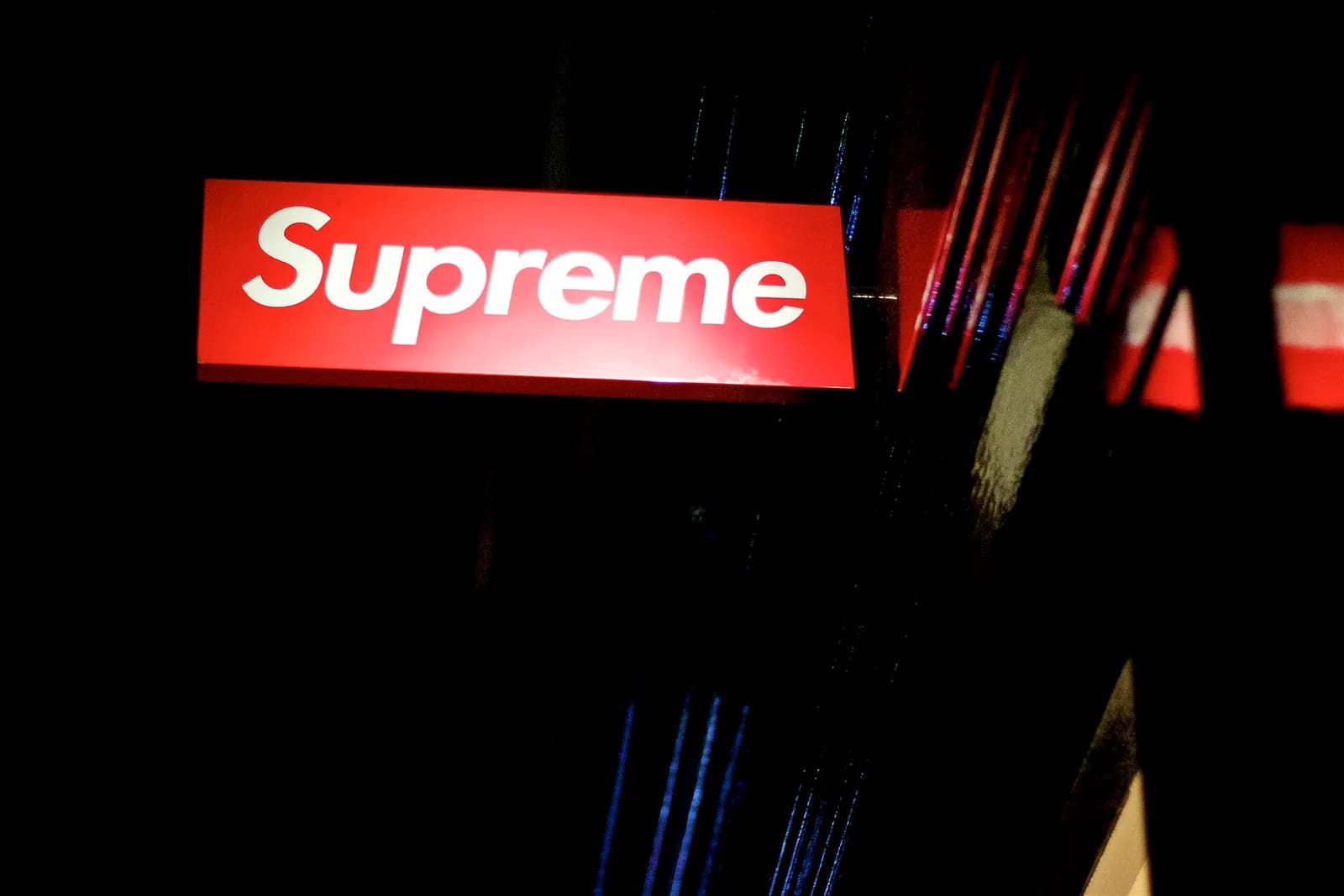 夜の店先に光る赤い長方形の看板。白い文字でSupremeとだけ書かれている