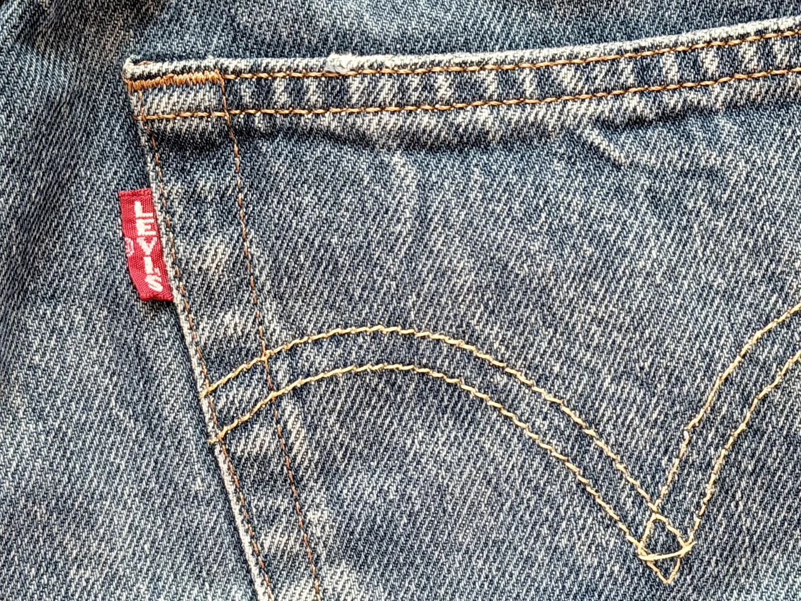 色落ちしたデニムの尻ポケット。赤いタブとアーチ状のステッチの接写
