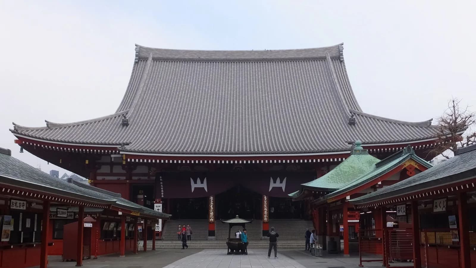 浅草寺の本堂。大きな瓦屋根の下に朱塗りの柱が並び、正面に紫の幕が下がっている