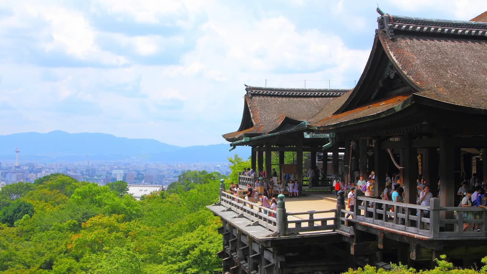 清水寺の本堂と舞台。崖から突き出した床を、下から組んだ木の柱が支えている。奥に京都の市街地が見える